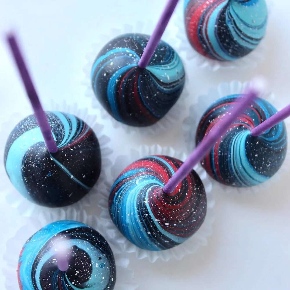 Dark galaxy cake pops with blue swirls and purple sticks - Popcakes Ottawa