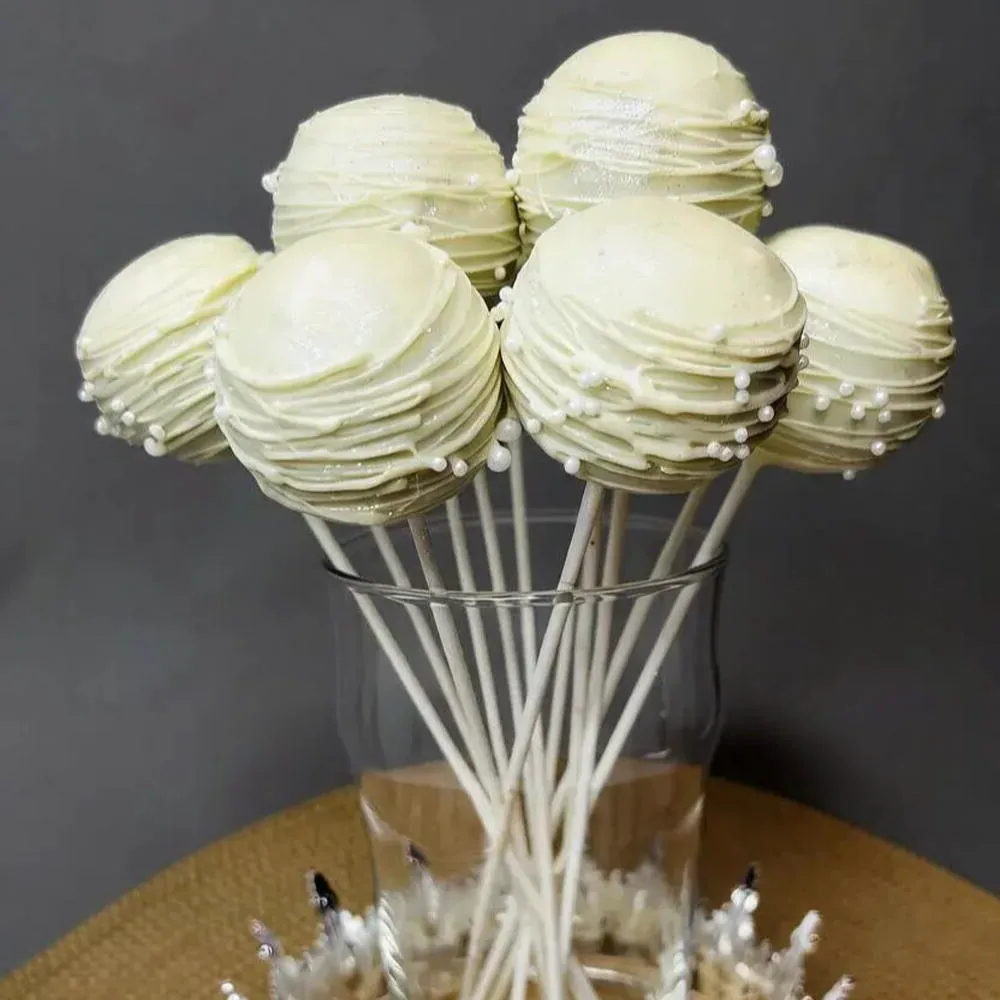 Ivory-coated cake pop arrangement with piped drizzle - Popcakes Ottawa