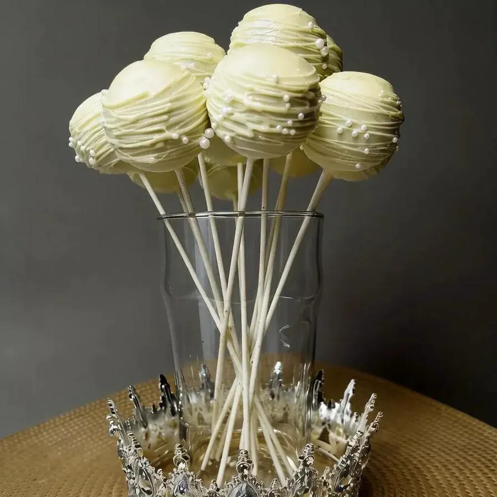 Ivory-coated cake pops with drizzle arranged in a clear glass - Popcakes Ottawa