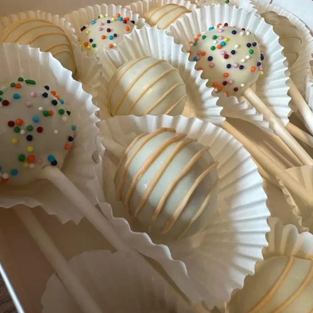 Close-up of white cake pops with orange drizzle and sprinkles - Popcakes Ottawa