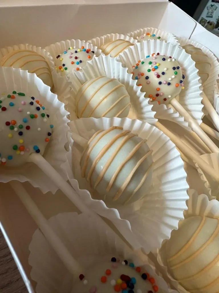 Close-up of white cake pops with orange drizzle and sprinkles - Popcakes Ottawa